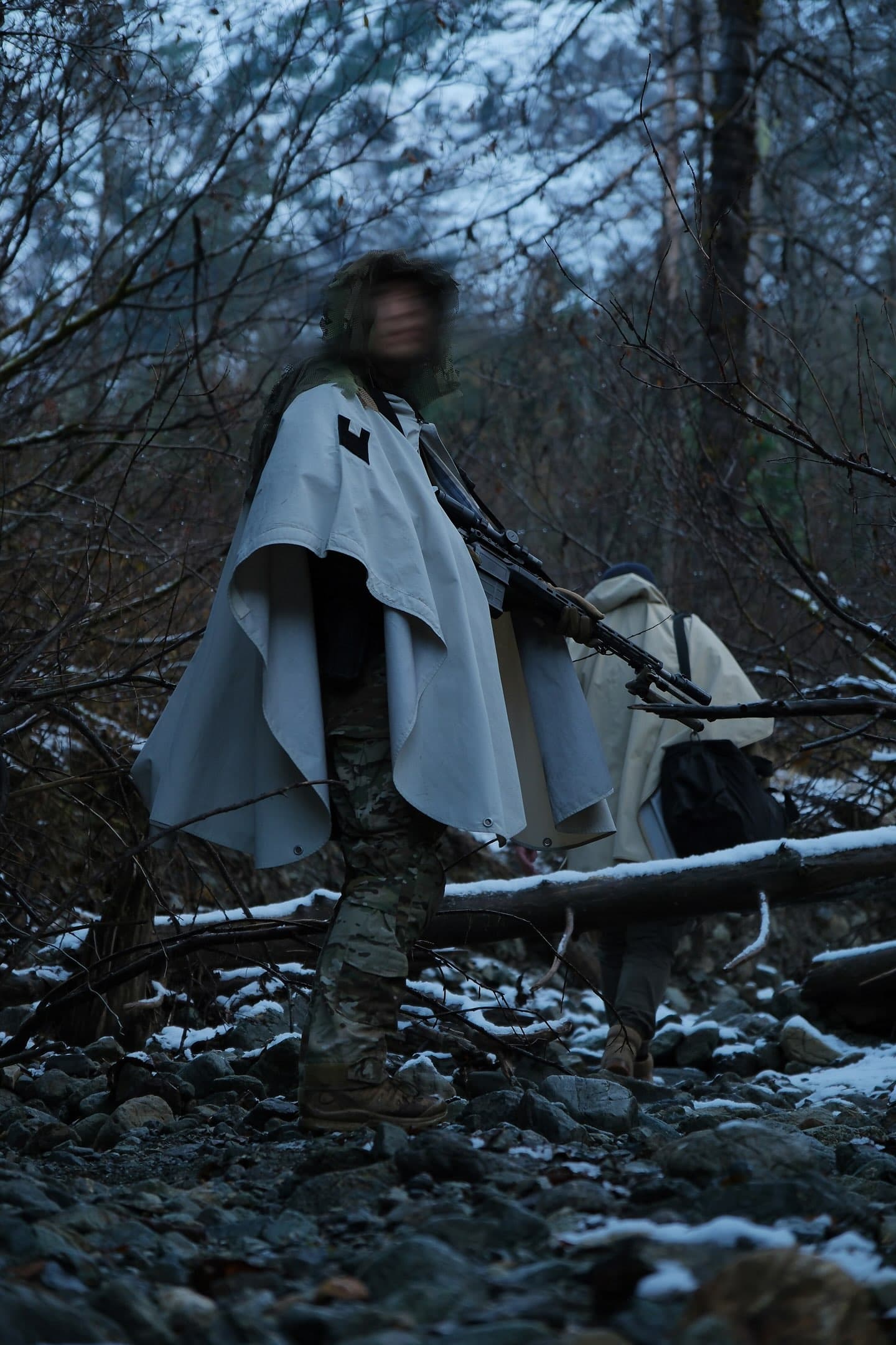Person in hooded gear during dusk in wilderness