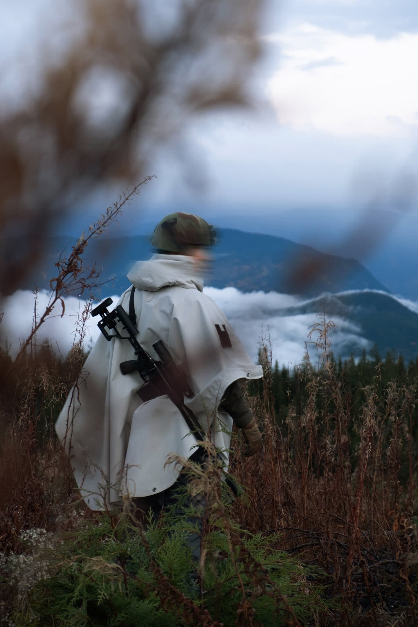 Two people in tactical gear silhouetted against misty landscape